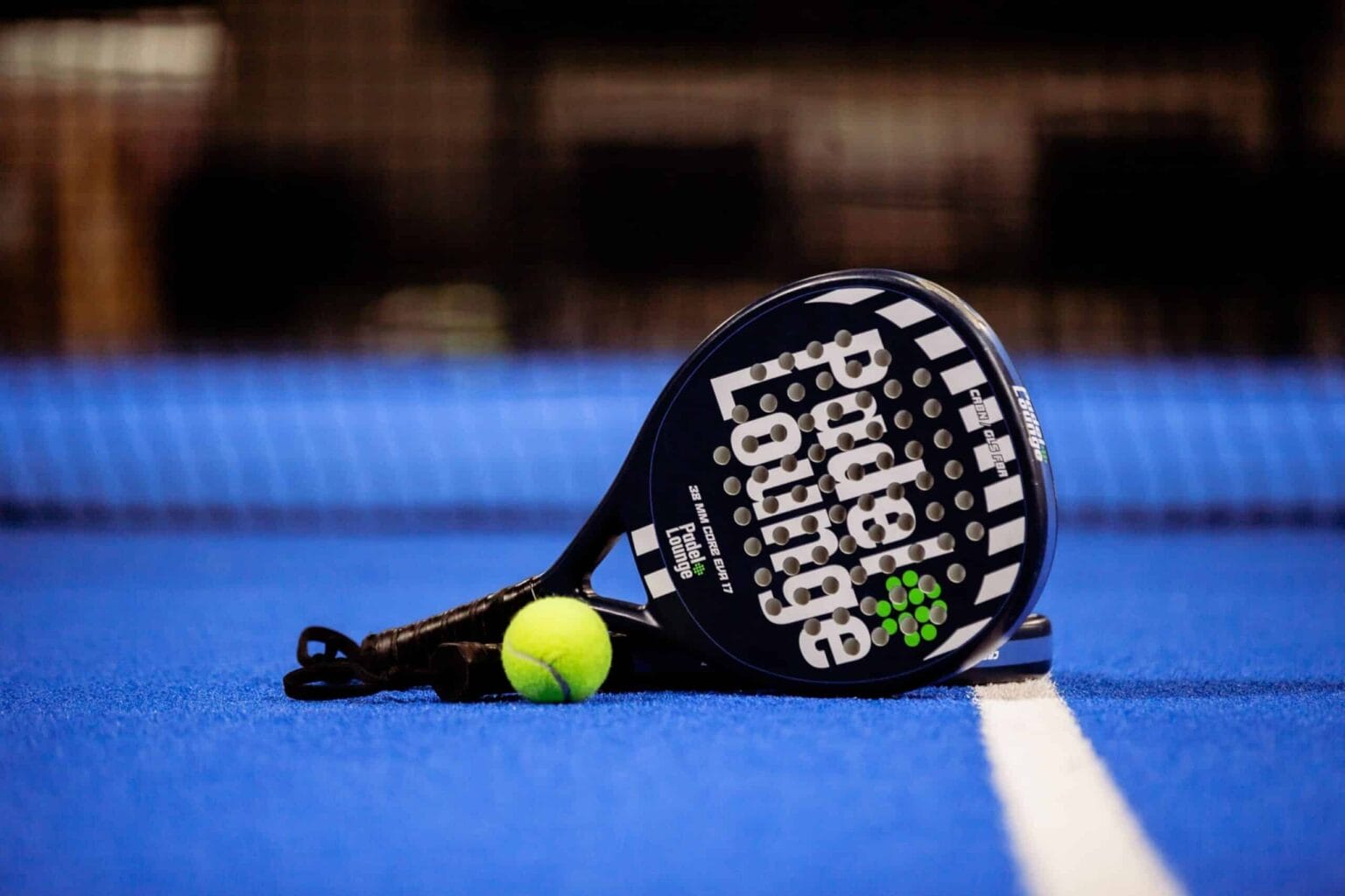 Padelbat og bold på blå bane