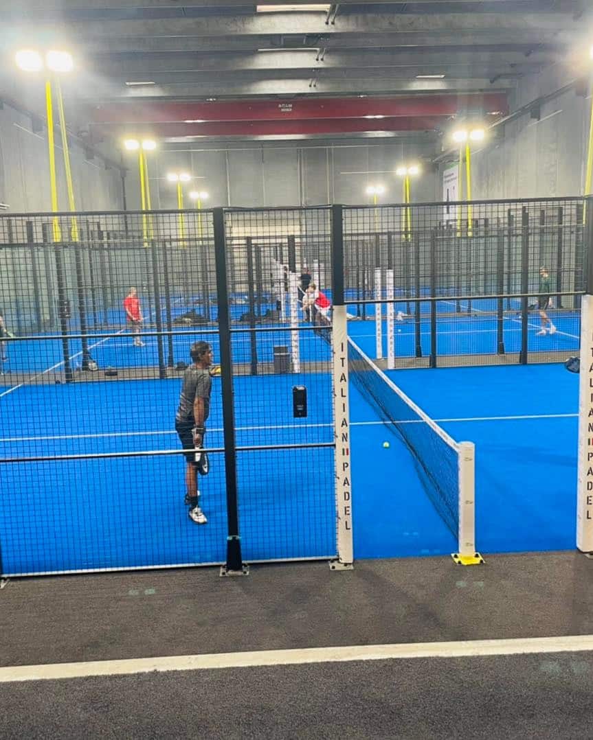 Folk spiller padel på indendørs blå baner